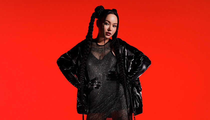 Bella Poarch dressed in black, posing in front of a red background (photo)