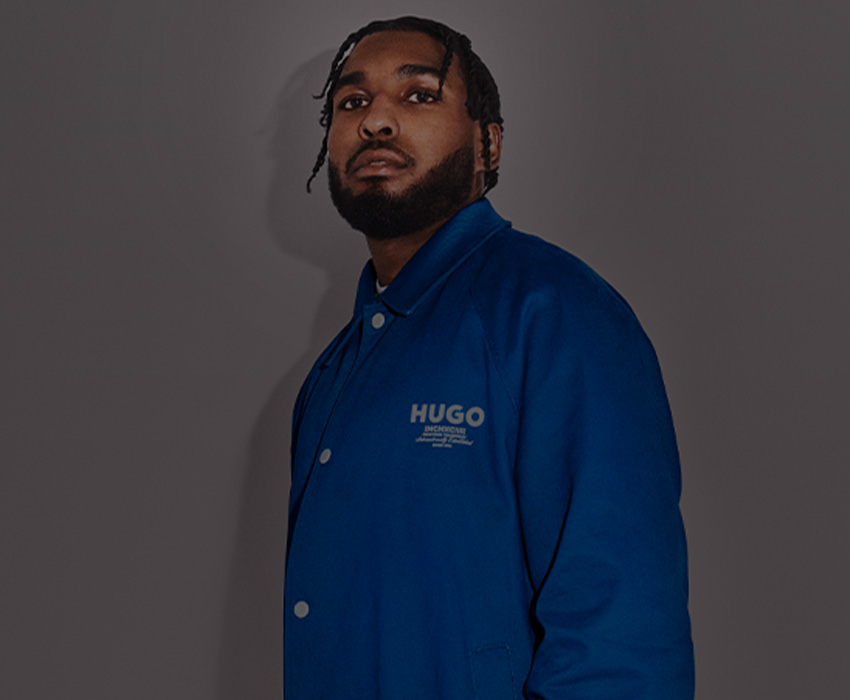 HUGO BLUE – Reezy dressed in blue, posing in front of a gray background, zoomed in (photo)
